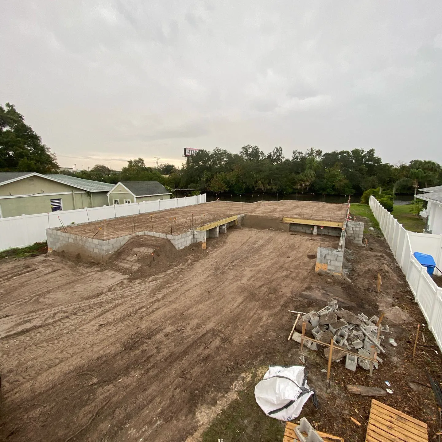 Compacted building pad beside a white fence line