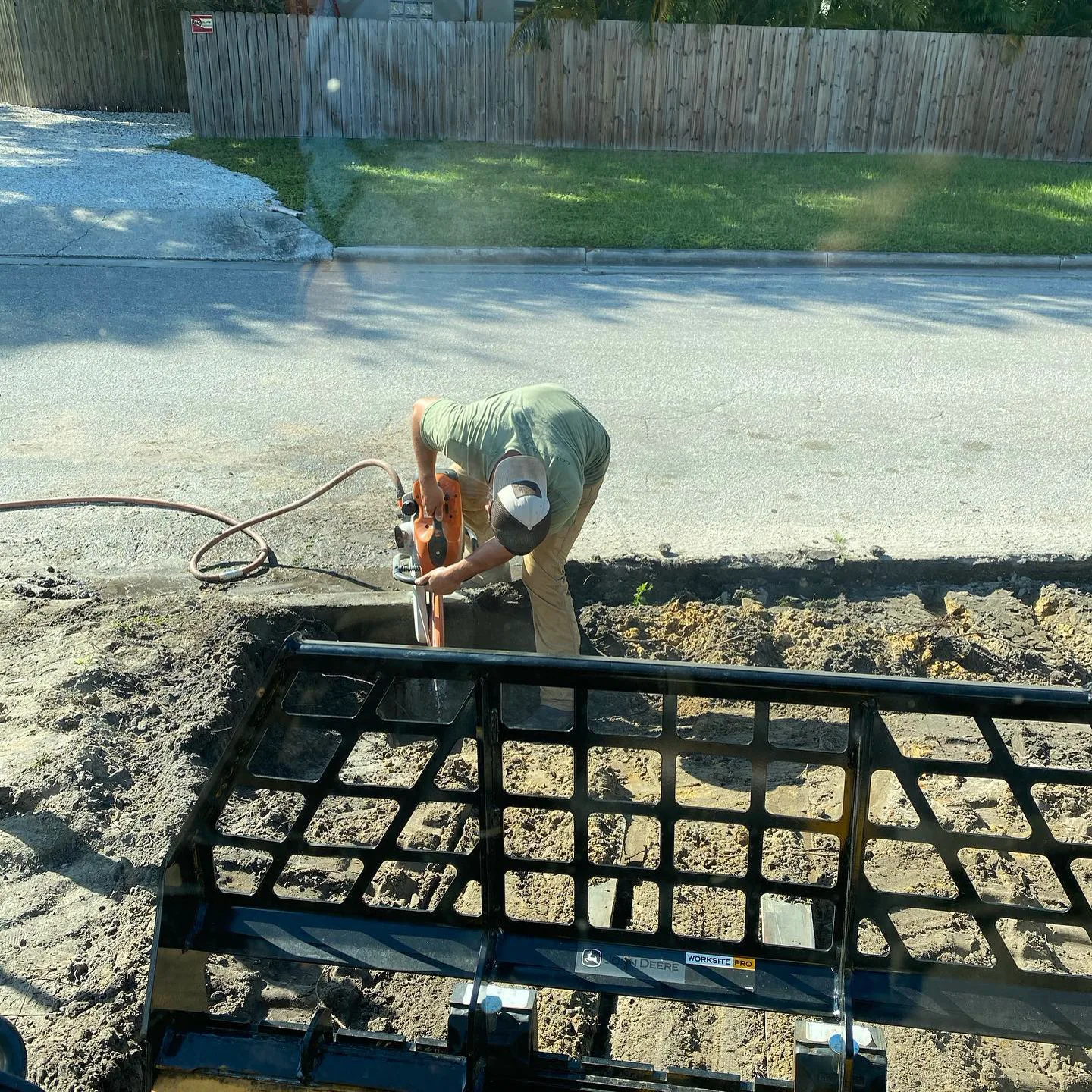 Plate compactor packing backfill over a finished drainage trench