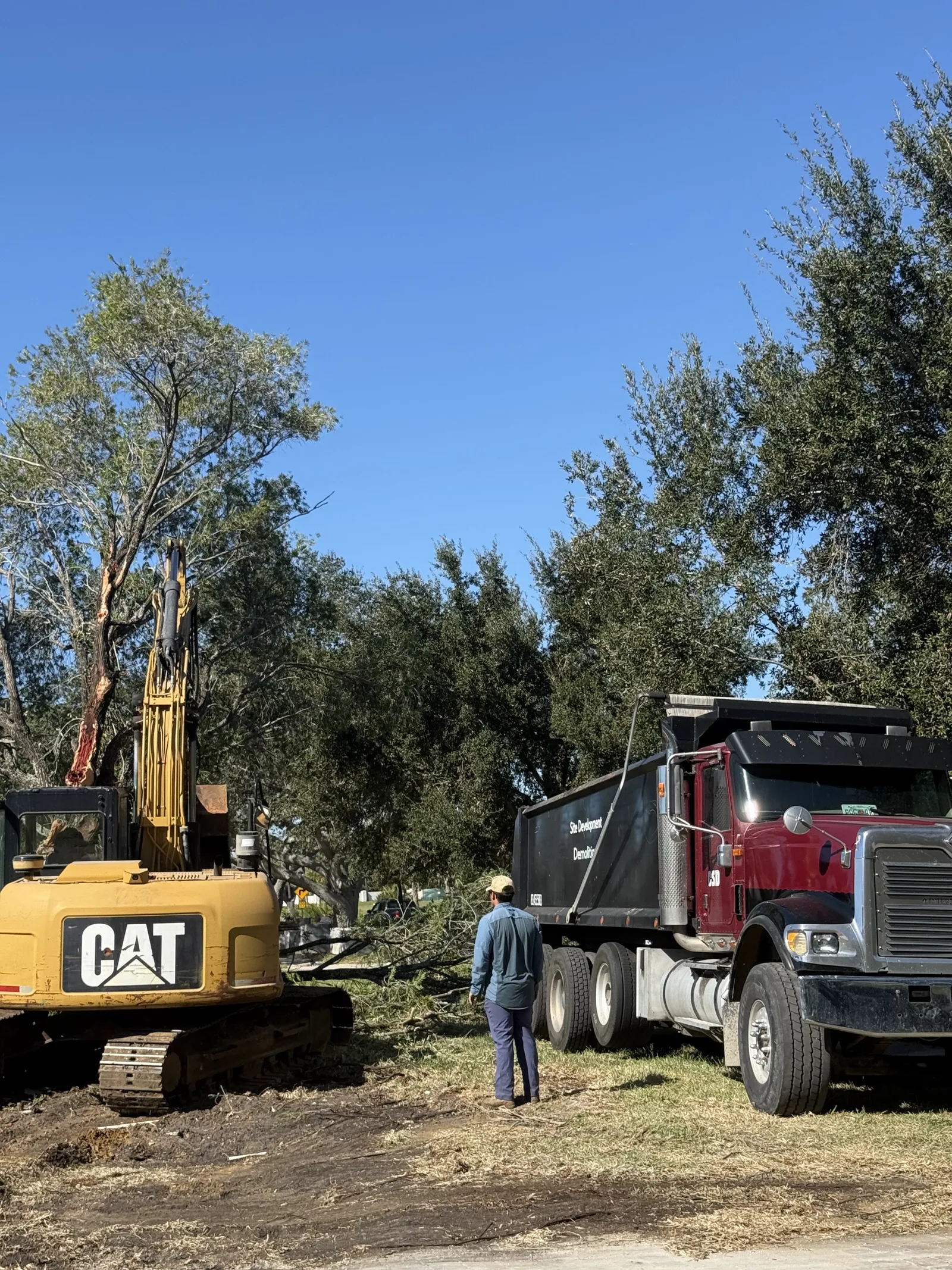 Excavator loading a dump truck during dirt hauling on a residential job