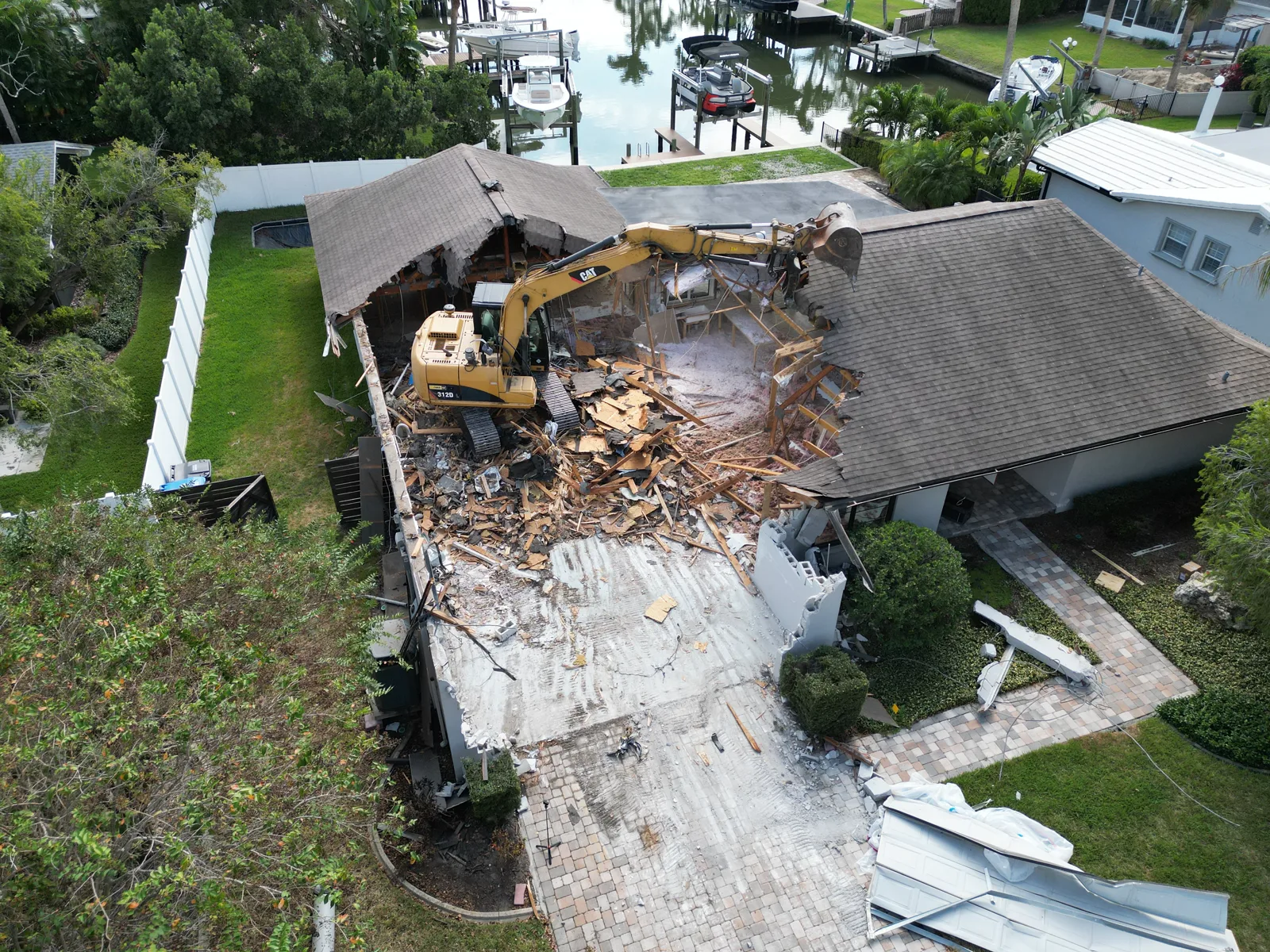 Excavator tearing into the roof of a house during a Tampa residential demolition