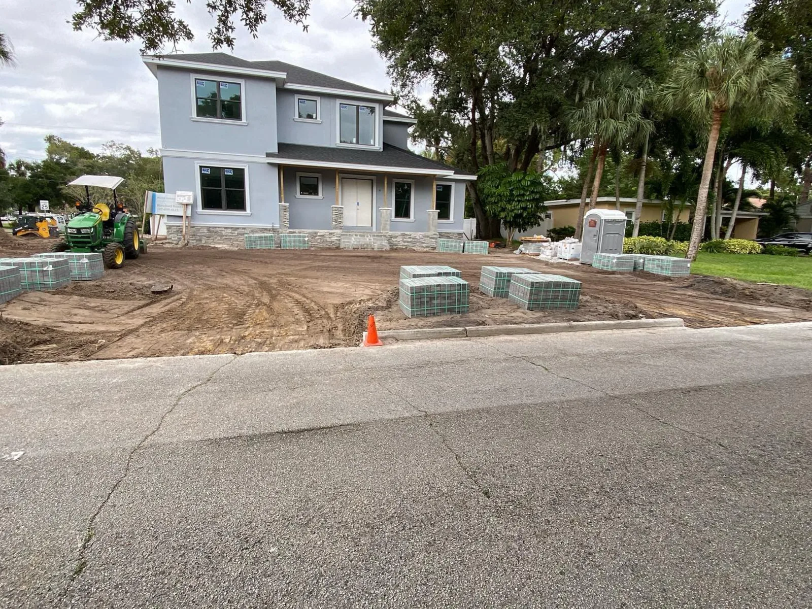 Mature oaks kept standing around a freshly graded lot beside a new house in Tampa