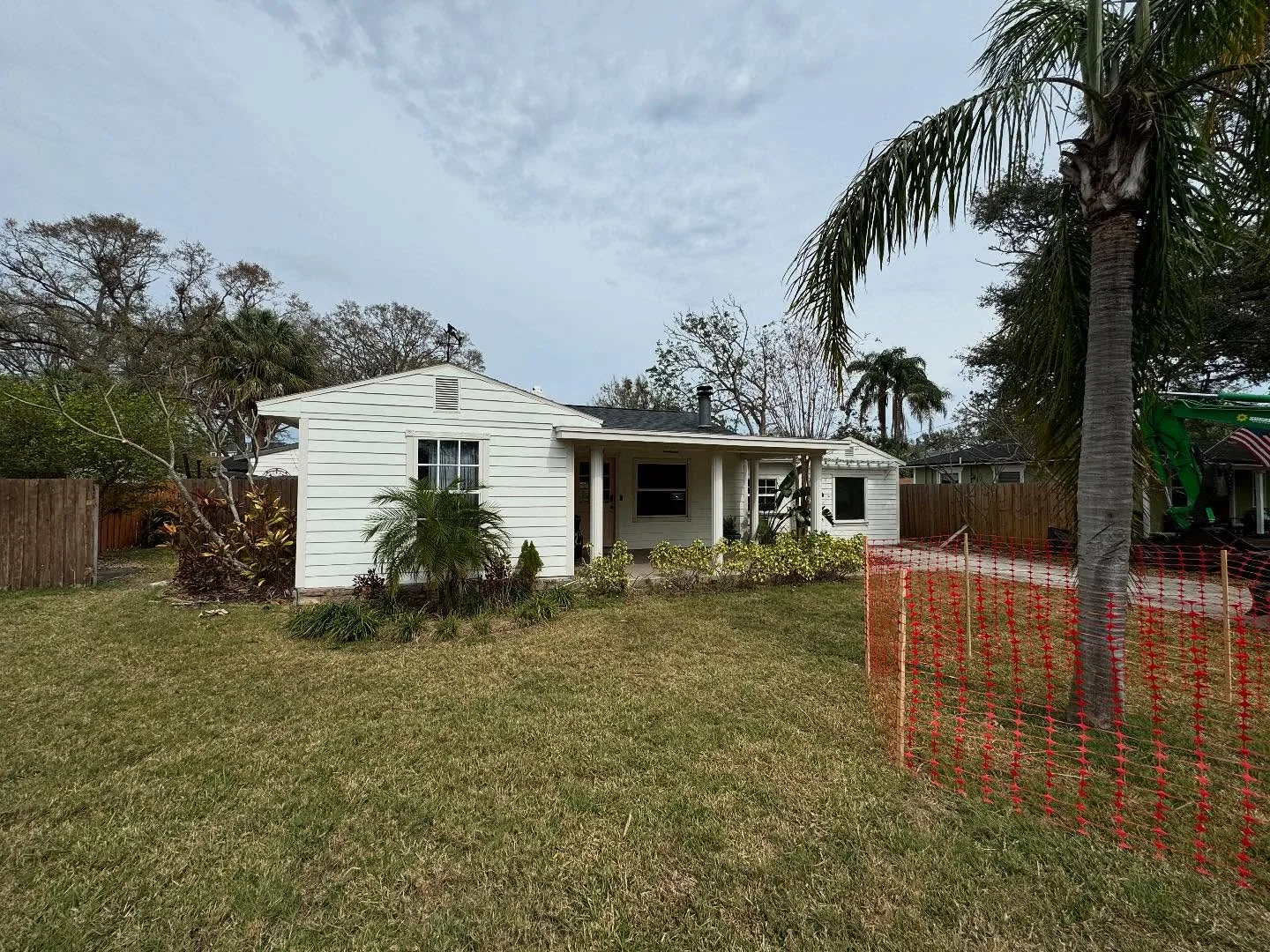 Storm damaged single story house fenced off with orange safety fencing before demolition